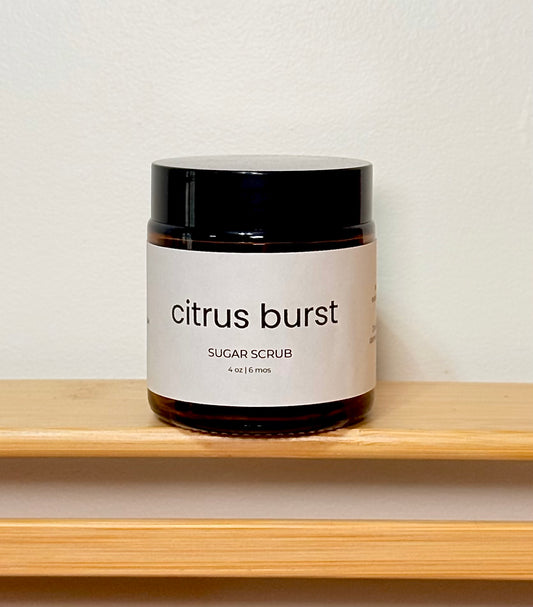 Jar of citrus burst sugar scrub on a wooden shelf with a white background