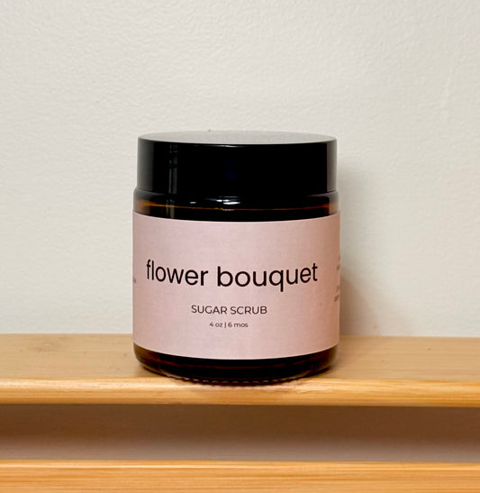 Jar of 'flower bouquet' sugar scrub on a wooden shelf with a light background