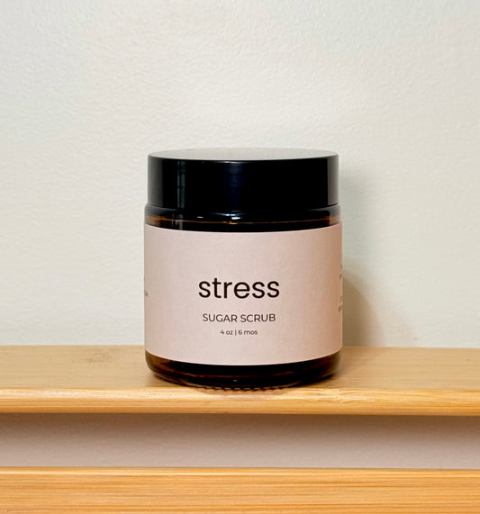 Jar of 'stress' sugar scrub on a wooden shelf with a neutral background