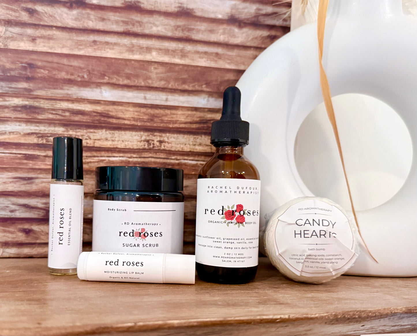 Collection of beauty products including bottles, jars, and a soap on a wooden surface with a wooden wall background.