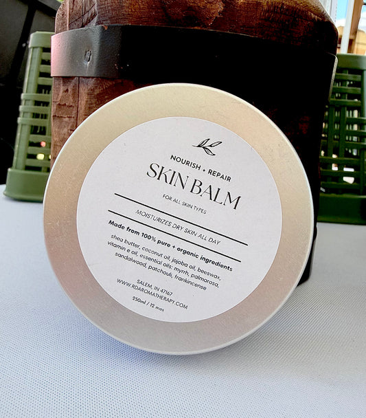 Skin balm tin with white label on a light surface with a wooden and green background.