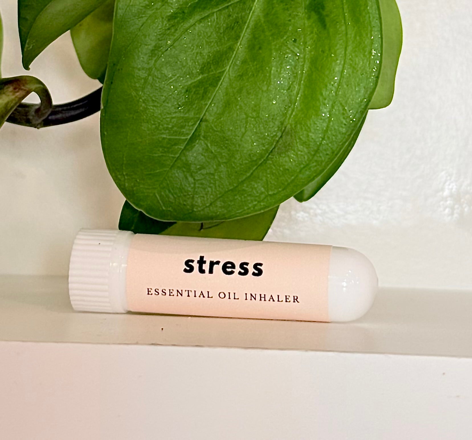 Essential oil Inhaler labeled 'stress' with green leaves in the background
