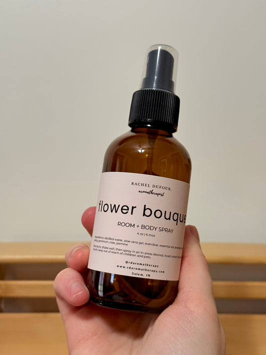 hand holding bottle labeled flower bouquet with a neutral background