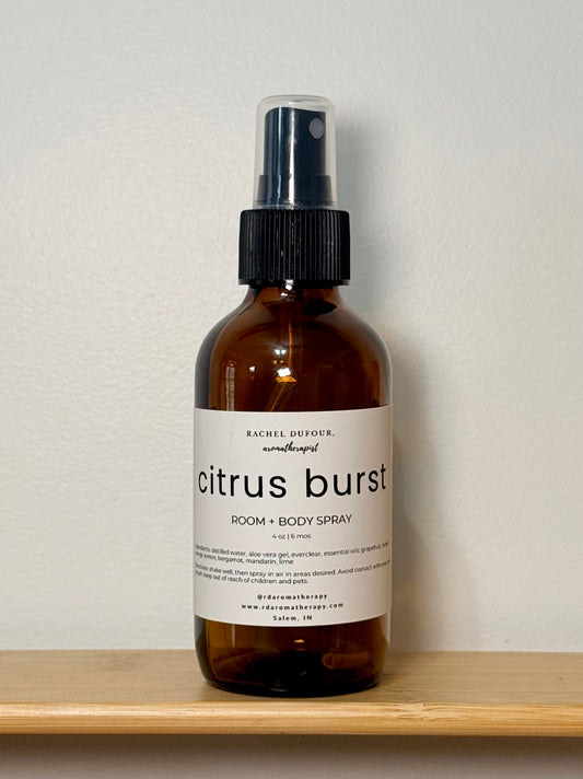 Brown spray bottle labeled 'citrus burst' on a wooden shelf with a light gray background