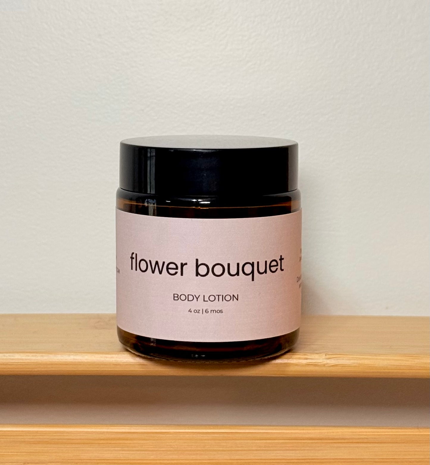 Jar of 'flower bouquet' body lotion on a wooden shelf with a neutral background