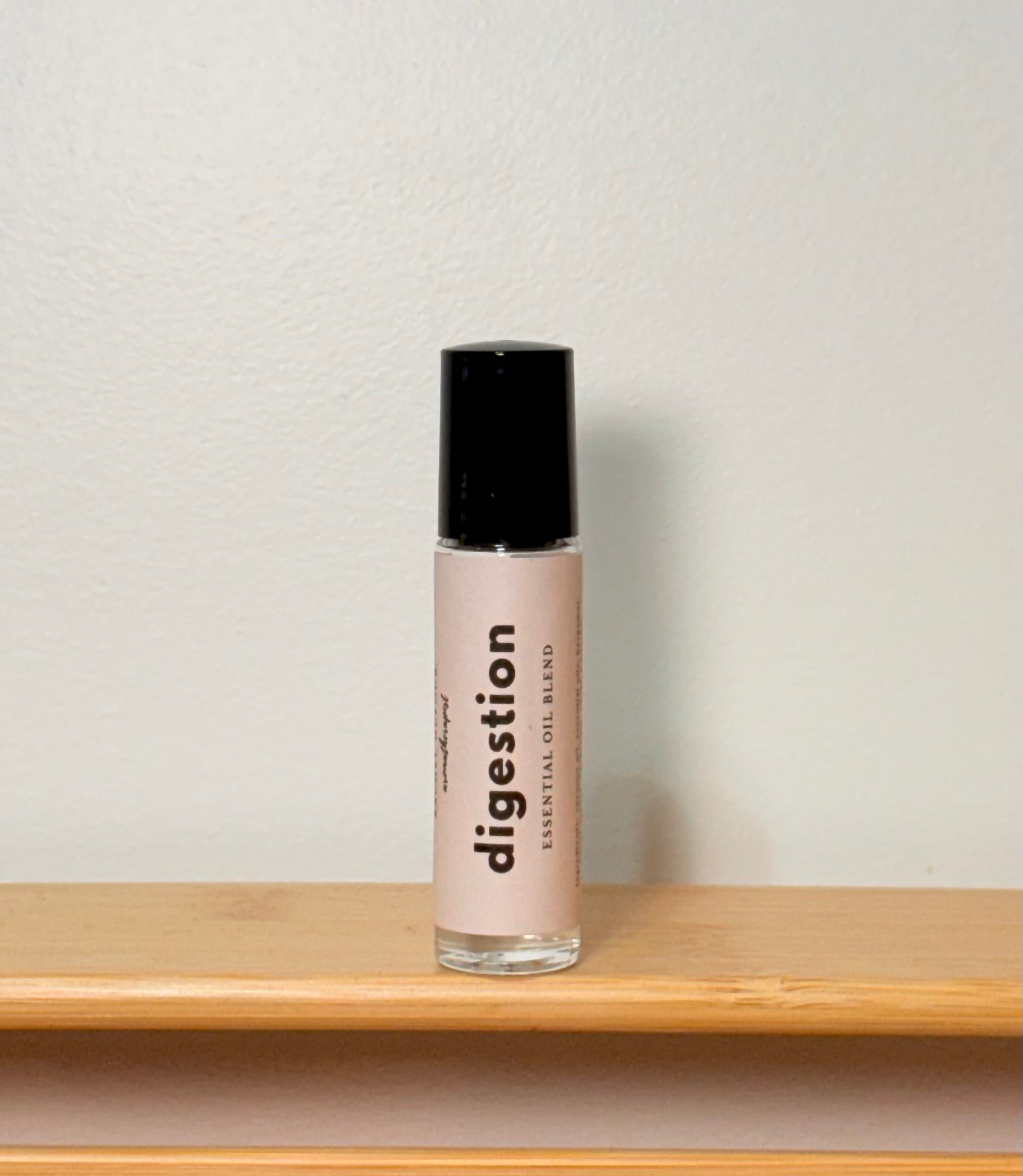 Roller bottle labeled "digestion" on a wooden shelf and neutral background