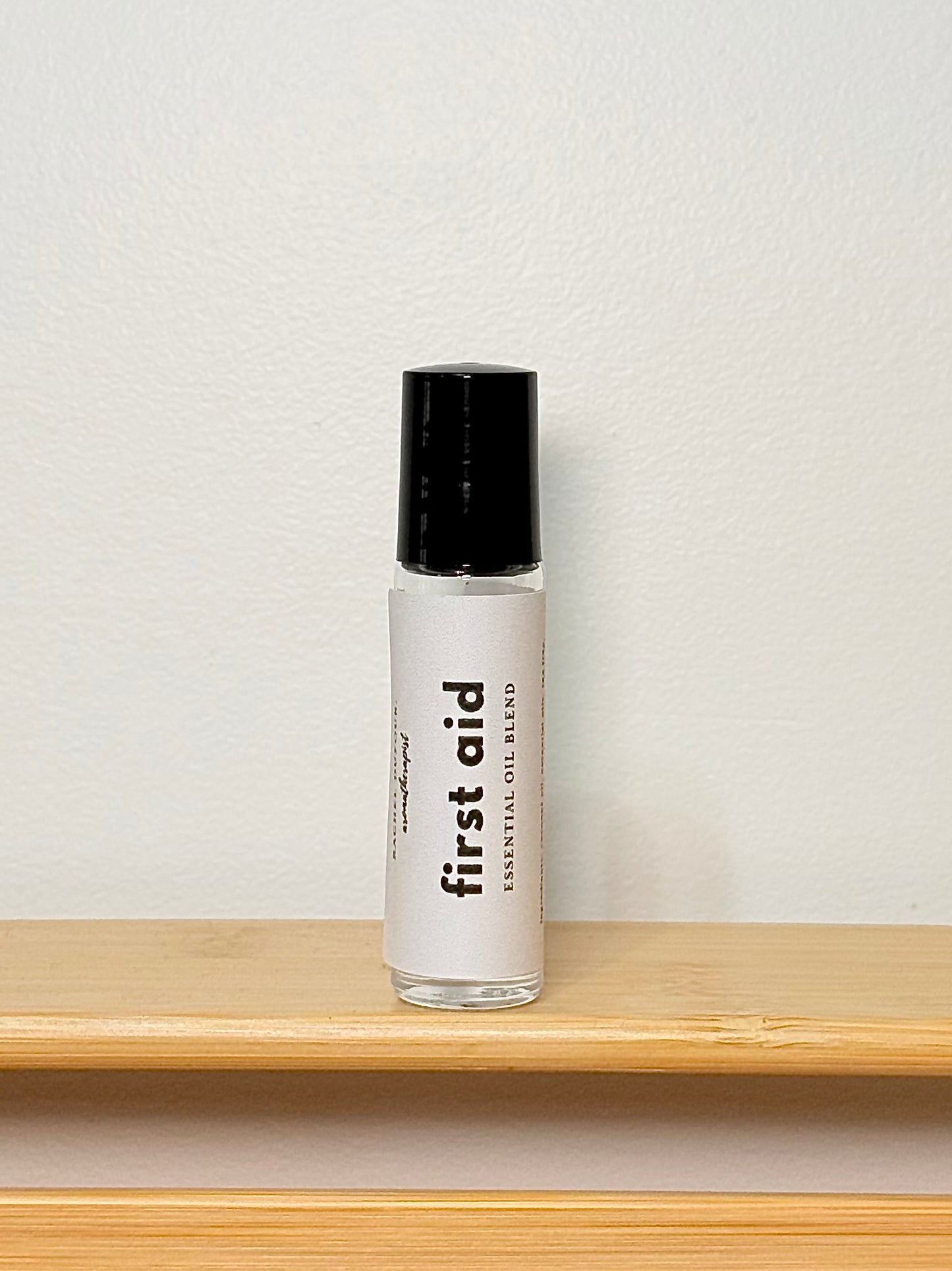 Bottle labeled 'first aid' on a wooden shelf with a light gray background