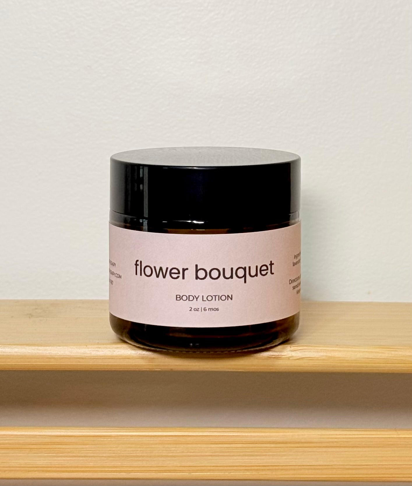 Jar of 'flower bouquet' body lotion on a wooden shelf with a light background