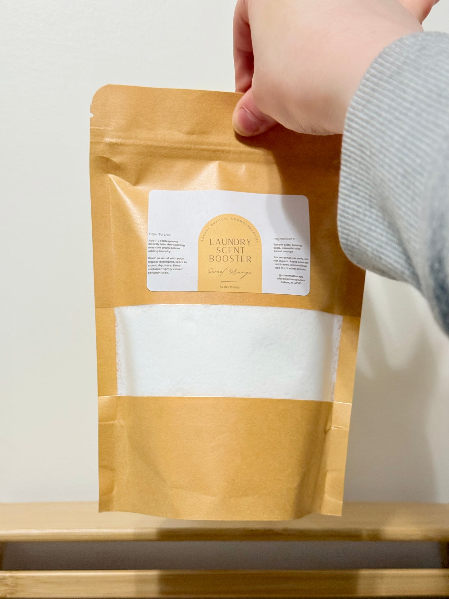 Kraft paper package of laundry aid booster with a hand holding it.