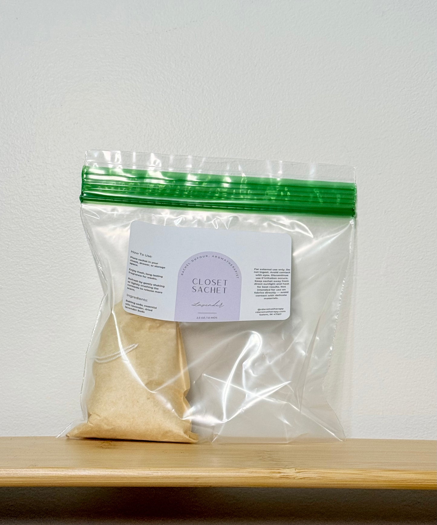 Clear plastic bag with a green zipper on a wooden surface, containing a beige powder and a label.