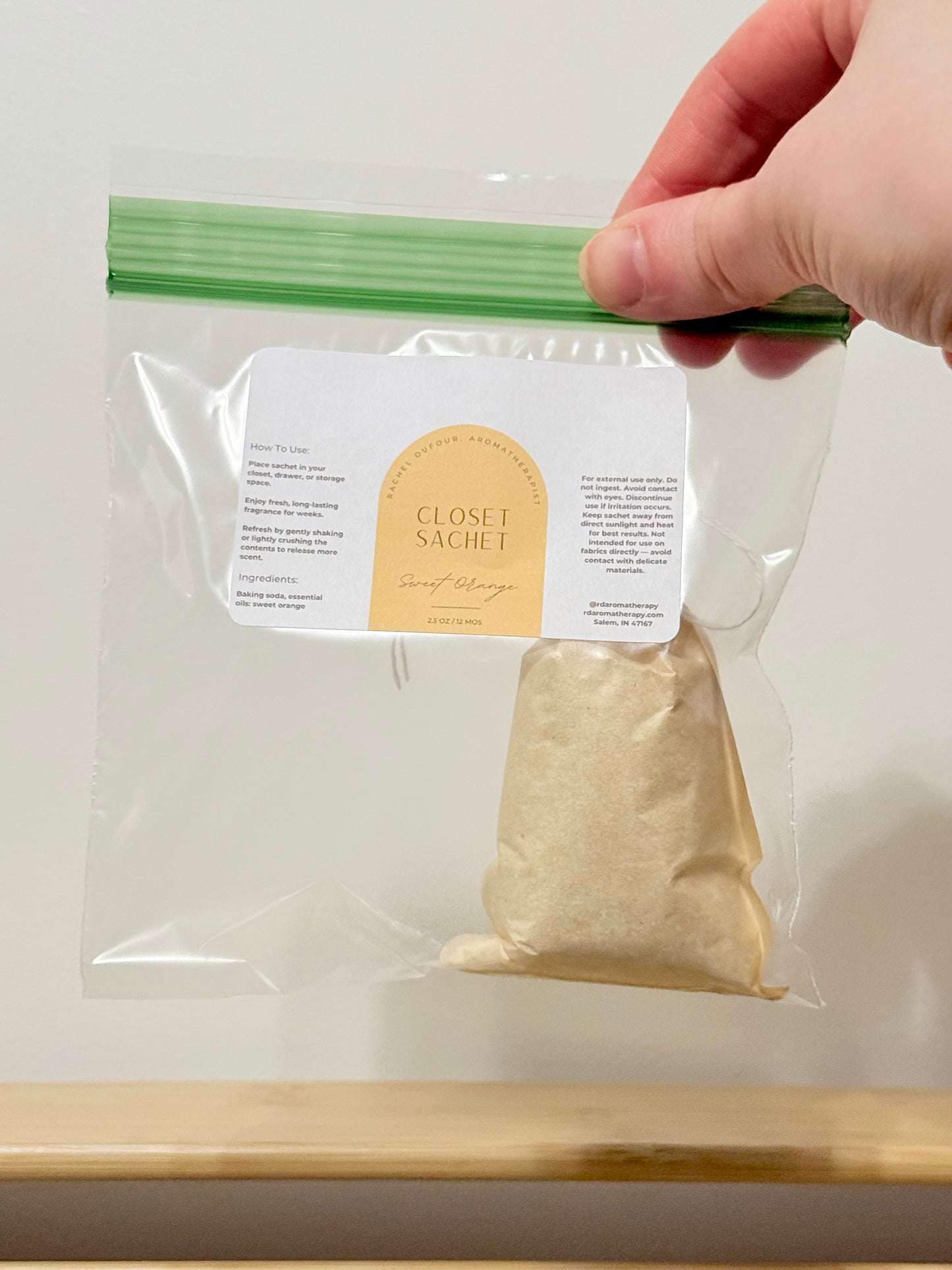 Closet sachet in clear packaging with a hand holding it against a white background