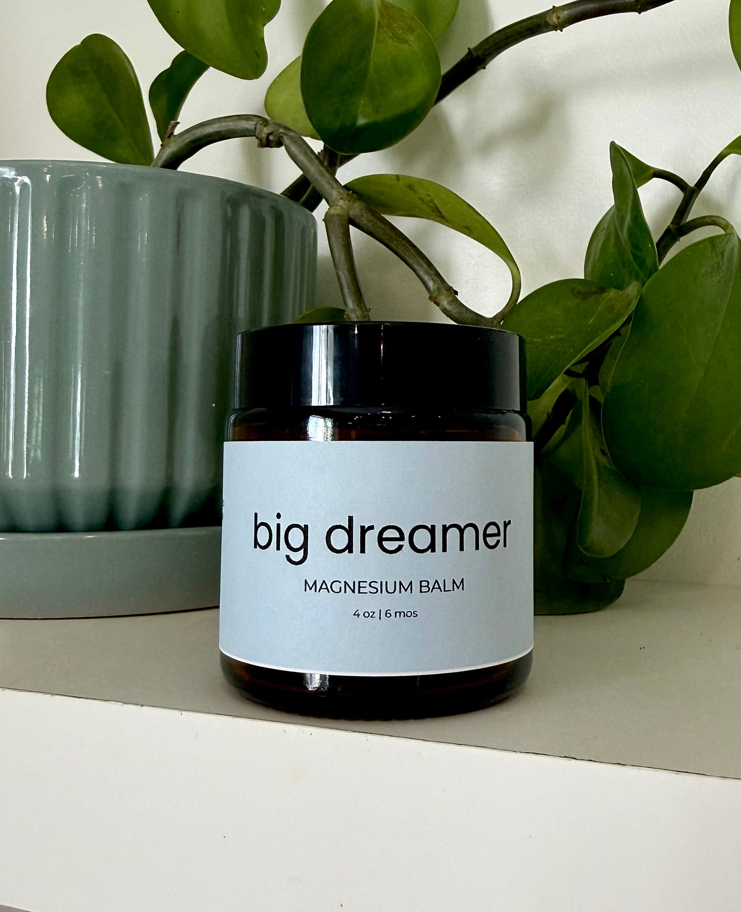 Jar of 'big dreamer' magnesium balm with a plant in the background
