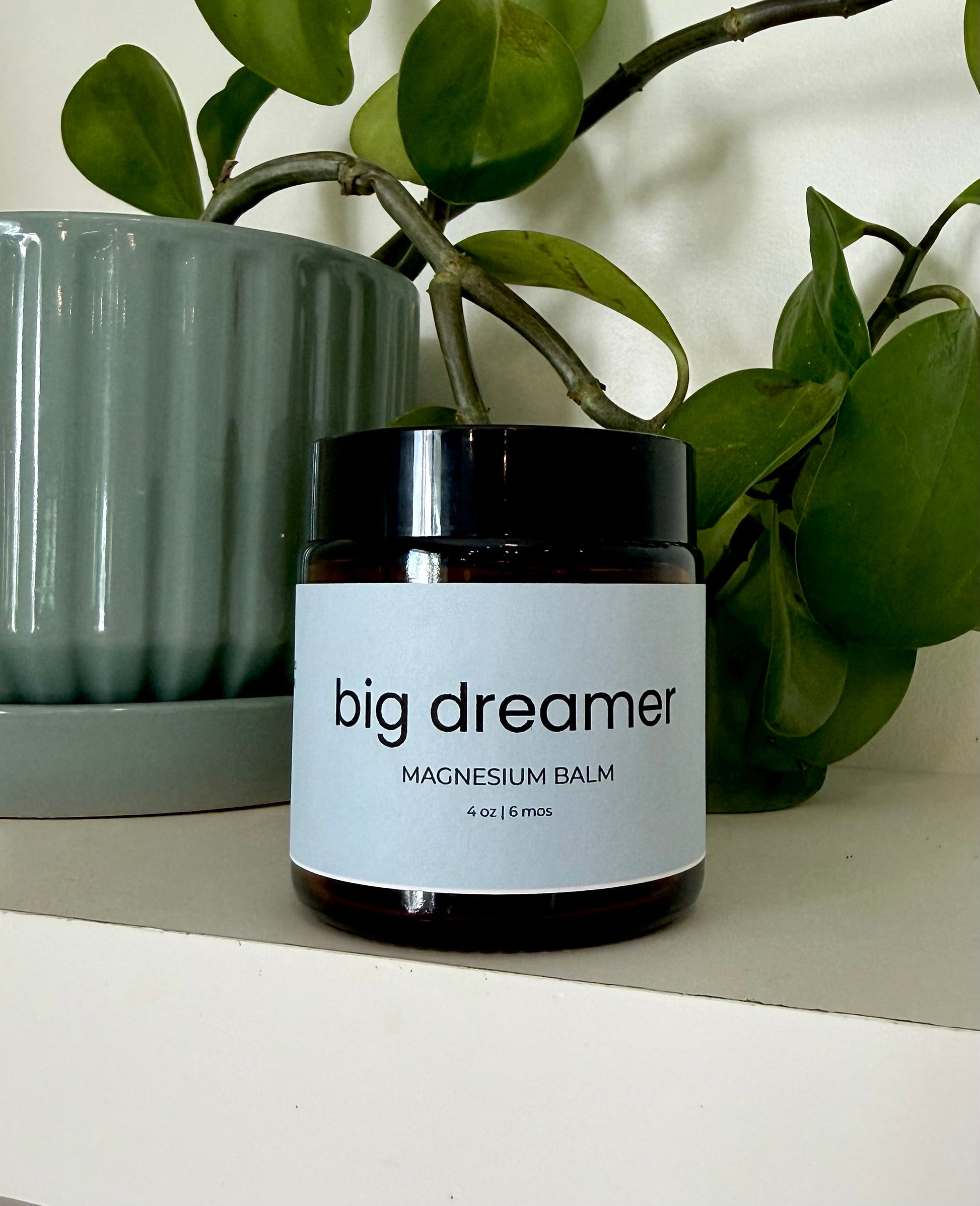 Jar of 'big dreamer' magnesium balm with a plant in the background