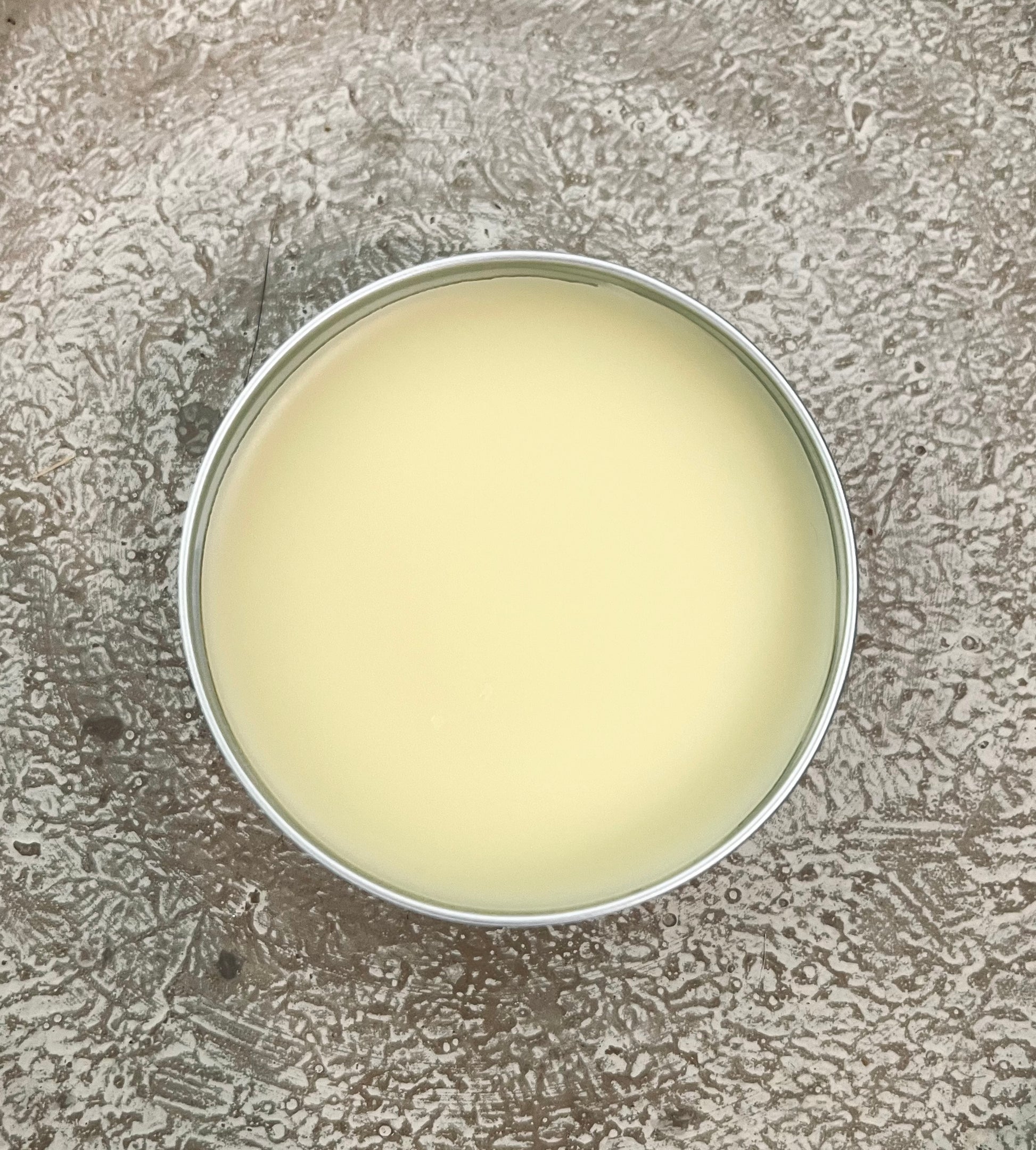 Round container with a white substance on a textured gray surface
